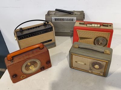 Plusieurs radios à l'ancienne sont posées les unes à côté des autres sur une table.