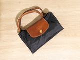 black and brown handbag on a wooden floor with a brown handle