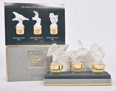 trois flacons de parfum posés sur une table à côté d'une boîte de parfums