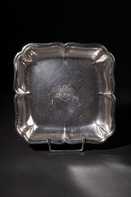 a silver plate on a black surface with a black background