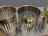 four silver cups and a tray on a table