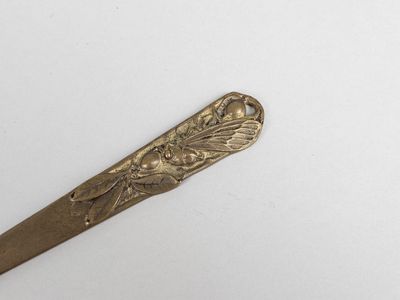 une cuillère en or ornée d'une fleur, posée sur un fond blanc
