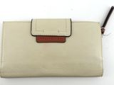 portefeuille en cuir couleur crème sur lequel repose un stylo