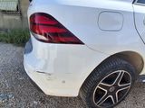 the rear end of a white car parked in a gravel lot