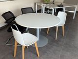 une table et des chaises blanches dans une salle équipée d'un tableau blanc