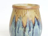 a close up of a small vase on a white surface