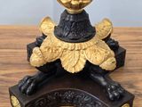 a gold vase on a black stand on a wooden table