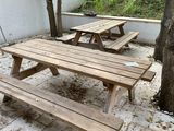 deux tables de pique-nique en bois au milieu d'une cour