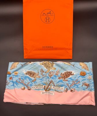 an orange shopping bag sitting on top of a table next to a pink bag