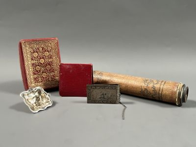 un livre rouge posé à côté d'une boîte rouge et d'un objet argenté