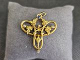 une image représentant une croix en or sertie d'une pierre bleue
