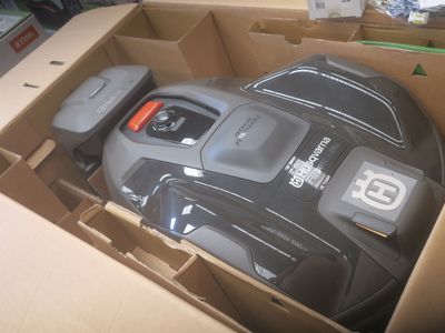 une boîte contenant une tondeuse à gazon noire et grise