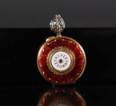 a close up of a red and gold pocket watch on a black surface