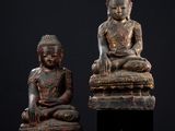 deux statues de bouddhas assis sur un socle noir
