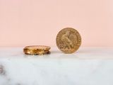 two gold coins sitting next to each other on a marble surface