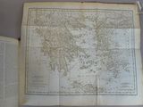 une vieille carte du monde posée sur une table, à côté d'un livre ouvert
