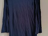 blue long sleeved shirt hanging on a hanger on a wall