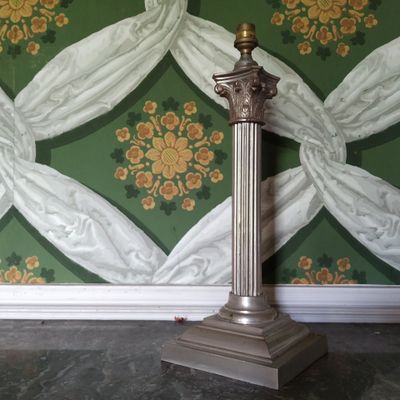 une lampe posée sur un socle devant un mur