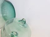 deux bocaux en verre vert avec leurs couvercles, posés sur une table