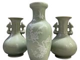 three green vases sitting next to each other on a white surface