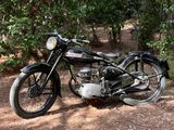 une moto noire garée sur le bord d'un chemin de terre