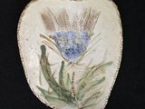 une photo d'une pierre décorative sur laquelle figure une fleur bleue
