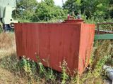 une boîte rouge rouillée posée au milieu d'un champ