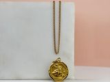 un collier en or avec une pièce d'or posée sur un bloc de marbre blanc