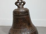 a bronze bell sitting on the floor next to a white wall