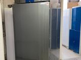 a silver refrigerator sitting in a room with blue lockers
