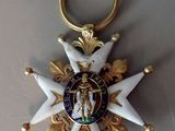 a gold and white star ornament hanging from a red ribbon