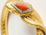 an image of a gold snake bracelet with a red stone in the middle