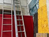 deux échelles appuyées contre un mur rouge