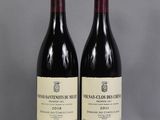 two bottles of red wine sitting next to each other on a table