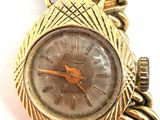 an image of a close up of a wrist watch with a chain around it