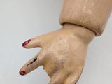 a wooden hand with red nails and a ring on it