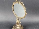 a small mirror with a bird on it on a stand