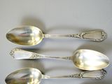 three silver spoons sitting on top of a table next to each other