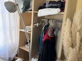 a room with a fan and clothes on a shelf