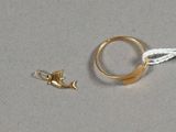 une bague en or ornée d'un poisson, à côté d'un cordon blanc