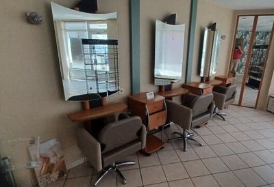 une photo d'un salon de coiffure avec des fauteuils et des miroirs