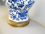 a blue and white vase with a gold base on a table