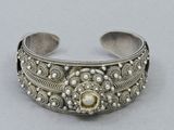 a close up of a silver bracelet with a stone in the center