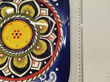 a blue plate with a yellow flower on it next to a ruler