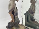 a statue of a woman holding a fish in front of a mirror