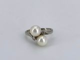 a close up of a white pearl and diamond ring on a white surface