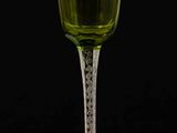 a green wine glass sitting on top of a wooden table