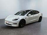 une Tesla Model 3 blanche garée dans une pièce blanche