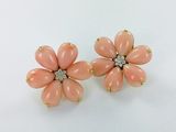 une paire de boucles d'oreilles en forme de fleur, de couleur corail, ornées de diamants