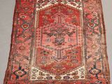 an antique rug with a red and blue design on a grey floor